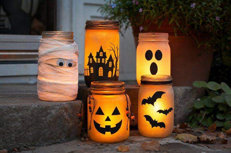 A cluster of glowing Halloween jar lanterns at different heights on a porch step at dusk — AI-generated image