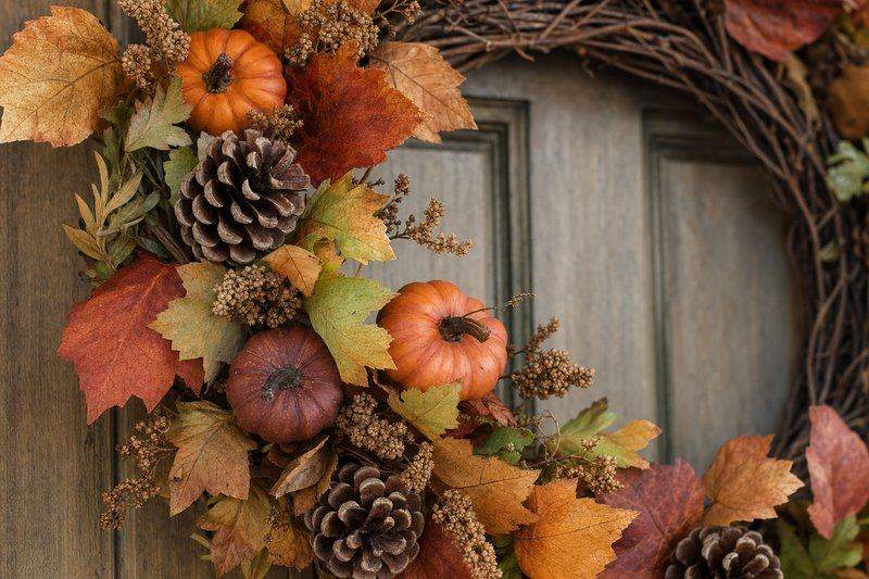 Close-up of a fall wreath made from dried leaves, mini pumpkins, and pinecones on a grapevine base — AI-generated image
