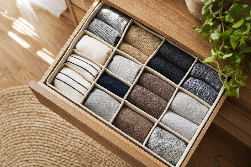 A drawer divider neatly separating rolled socks into ankle, dress, and athletic categories — AI-generated image