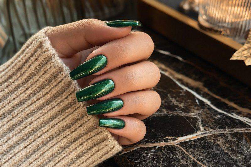 A hand with long coffin-shaped nails in bold emerald green with a chrome shimmer topcoat — AI-generated image