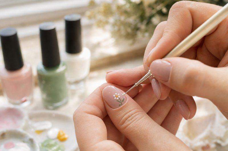 A hand using a small dotting tool to paint a tiny flower design on a nail — AI-generated image