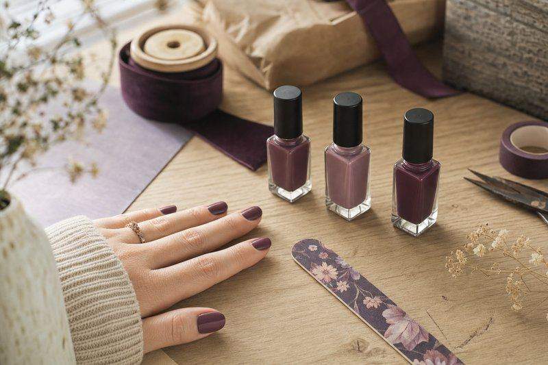 A close-up of a manicured hand next to a nail file and a few nail polish bottles — AI-generated image