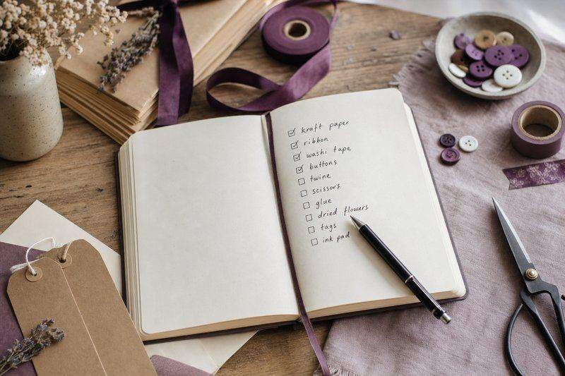 An open notebook with a handwritten checklist of craft supplies and a pen — AI-generated image